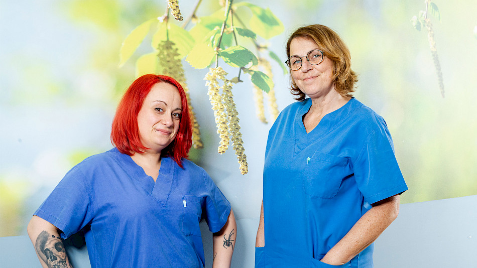 Zwei Pflegekräfte vor Wand mit Fototapete